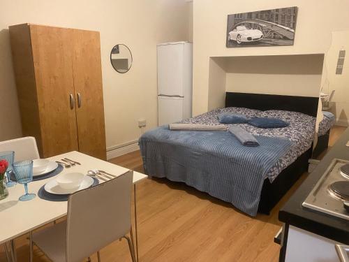 a room with a bed and a table and a kitchen at Studio flat/Close to central in Hendon