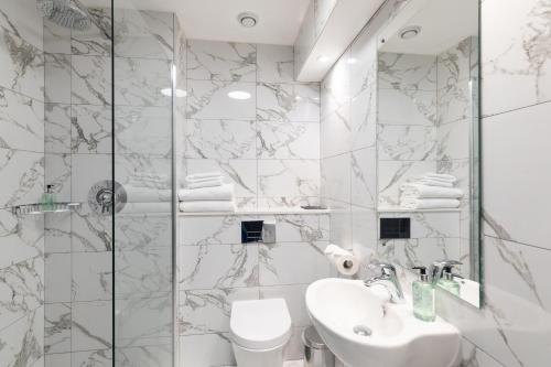 a white bathroom with a sink and a shower at The Sir Thomas Hotel in Liverpool