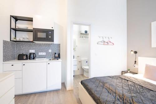 ein weißes Schlafzimmer mit einem Bett und einem Badezimmer in der Unterkunft Extreme Central - Modern Mini Studio in Budapest