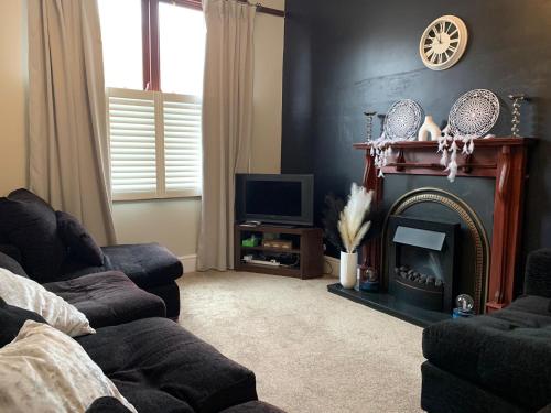 a living room with a fireplace and a tv at Beautifully Styled 2BR Home with Garden in Manchester