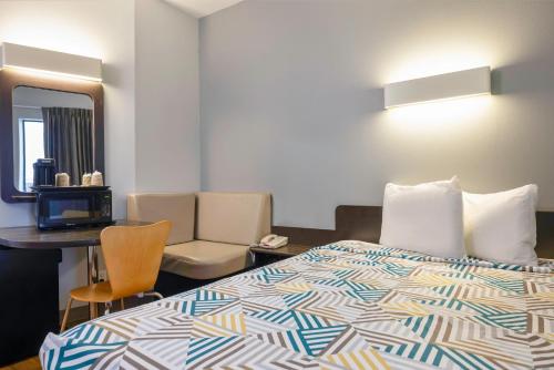 a hotel room with a bed and a desk and a mirror at Motel 6 Texas City I-45 in Texas City