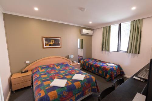 a hotel room with two beds and a desk at Chadstone Executive Motel in Oakleigh