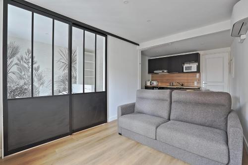 un salon avec un canapé et une grande fenêtre dans l'établissement Appartement Gambetta - Welkeys, à Biarritz