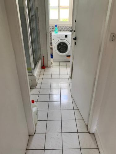 een wasruimte met een wasmachine en een tegelvloer bij Une Chambre très proche de Paris in Ivry-sur-Seine