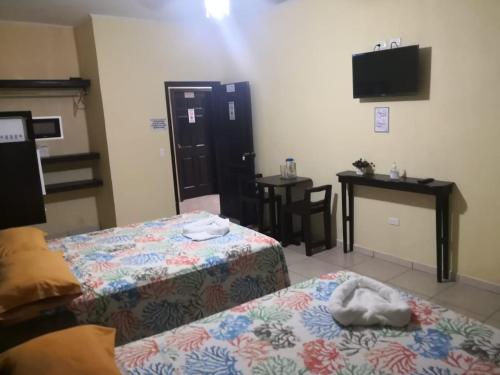 a room with two beds and a table and a television at B Aparts Hotel in Coxen Hole