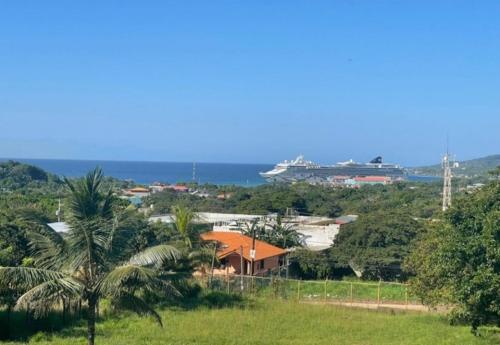 a house with a view of the ocean and a cruise ship at B Aparts Hotel in Coxen Hole