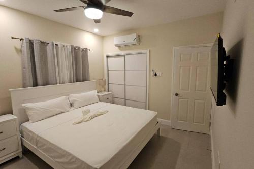 - une chambre avec un lit blanc et un ventilateur de plafond dans l'établissement Casa Fortuna in Lucea, Hanover, à Point