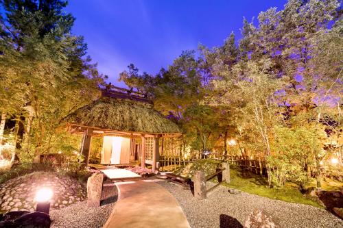 a home with a thatch roof and a pathway at Satonoyu Waraku 13 years or older in Minamioguni