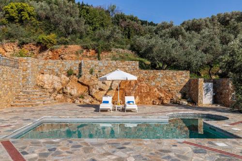 two chairs and an umbrella next to a pool at RODON Luxury Villas in Skopelos Town