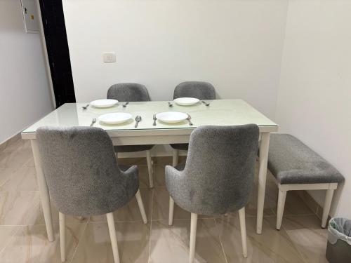 a dining room table with four chairs and a white table at Luxury Inn: 2BR Prime location in Madinaty B12 in Madinaty