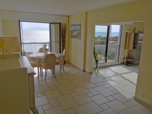 - une cuisine et une salle à manger avec une table et une vue sur l'océan dans l'établissement Le Grand Panoramique - Face Mer, à Les Sables-dʼOlonne