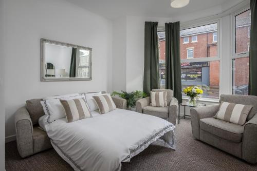 a bedroom with a bed and two chairs and a window at Blackpool Central Springfield Apartments Spacious Comfort in Blackpool