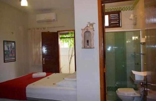 a bedroom with a bed and a bathroom with a toilet at Pousada Munguba in Jericoacoara