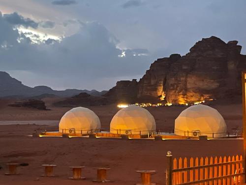 three domes in the desert with mountains in the background at Golden mountains camp in Wadi Rum