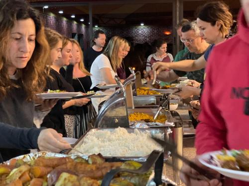 a group of people getting food at a buffet at Golden mountains camp in Wadi Rum