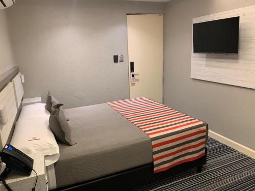 a hotel room with a bed and a flat screen tv at Benjamín I in San Salvador de Jujuy