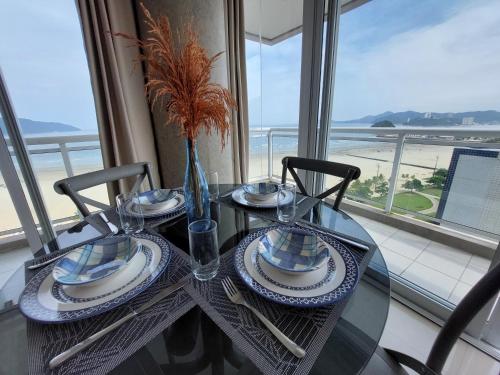 a table with plates and utensils on a table with a window at Book Santos - Unlimited 1419 - Studio Frente Mar in Santos