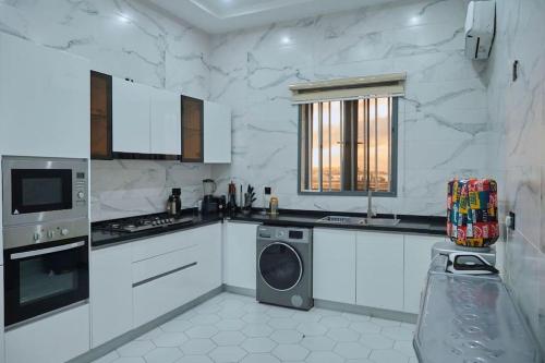 a white kitchen with a washing machine in it at Exquisite 3BR Penthouse with Waterfront Views in Lekki