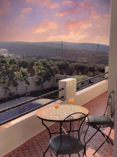a table and chairs on a balcony with a view at Vila Haja - Beautiful Farmhouse with a Private Pool! in Imouzzer Kandar