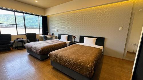 a hotel room with two beds and a desk and chair at Yufuin Akarinoyado in Yufuin