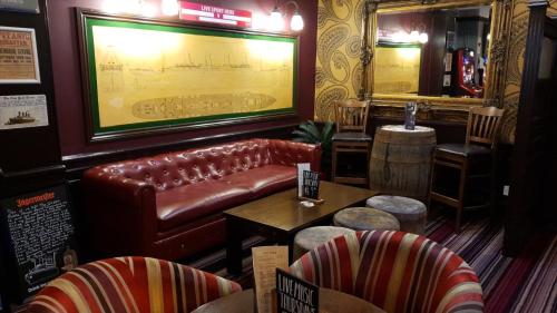 The Grapes Pub في ساوثهامبتون: يوجد بار به أريكة جلدية وطاولات وكراسي