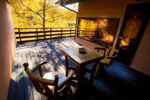 a wooden table and chairs on a porch with a fireplace at Satonoyu Waraku 13 years or older in Minamioguni