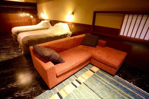 a hotel room with a couch and a bed at Satonoyu Waraku 13 years or older in Minamioguni