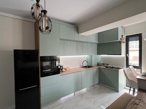 cocina con armarios verdes y nevera negra en Apartament Andreea, en Mamaia Nord – Năvodari