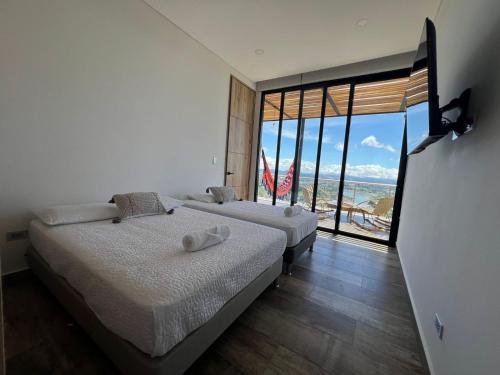 two beds in a room with a view of the ocean at Montecielo Hosting in Guatapé