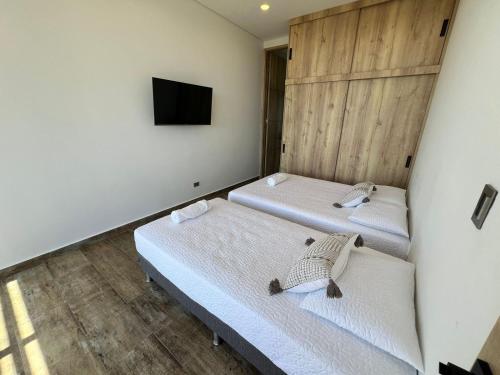two beds in a room with a tv on the wall at Montecielo Hosting in Guatapé