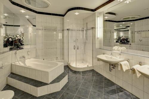 a white bathroom with a tub and a sink at Hotel La Strada in Kassel