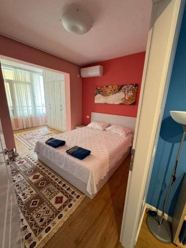 ein Schlafzimmer mit einem Bett und einer roten Wand in der Unterkunft Tirana Centre New Lions Gate 3 Apartment in Tirana