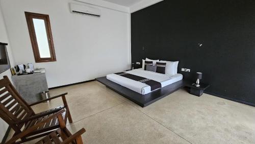 a bedroom with a bed and a black wall at Ariya Tissa in Tissamaharama