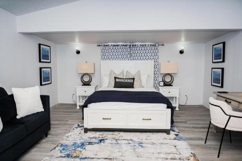 a bedroom with a white bed and a black couch at Villa 409C in Jolly Harbour