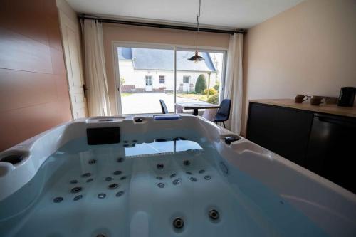una gran bañera blanca en una habitación con ventana en Suite & SPA privatif Domaine des Demoiselles, en Hauteville