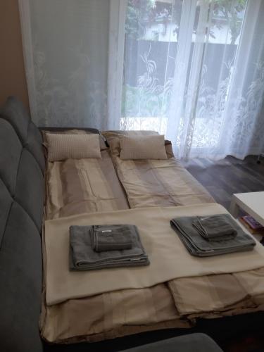 a bed with two trays on it in front of a window at Cozy apartment close to the airport in Budapest