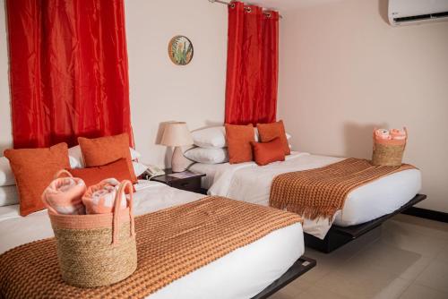 two beds in a room with red curtains and red curtains at Sunset Harmony, Your Escape at Playa Hermosa in Sardinal