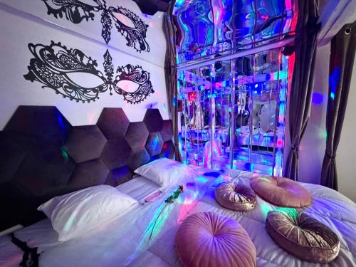 a bedroom with a bed with masks and colored lights at Caporizon-Lov'BNB-La seule Love House de Dordogne in Biras