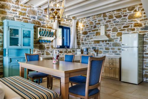 a kitchen with a wooden table and blue chairs at RODON Luxury Villas in Skopelos Town
