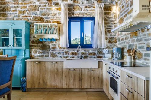 a kitchen with wooden cabinets and a stone wall at RODON Luxury Villas in Skopelos Town