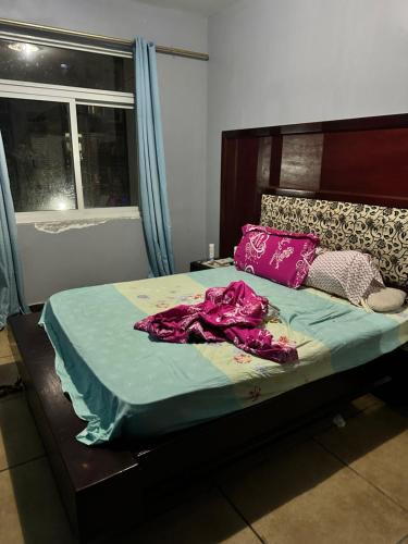 - une chambre avec un lit doté de draps violets et une fenêtre dans l'établissement Maqueda 2. Sanjo, à Malabo