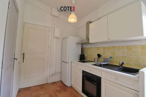 une cuisine avec des armoires blanches et un réfrigérateur blanc dans l'établissement Les figuiers - 4 couchages, à Carry-le-Rouet