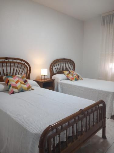 een slaapkamer met 2 bedden en een tafel met een lamp bij La Aurora in Camariñas