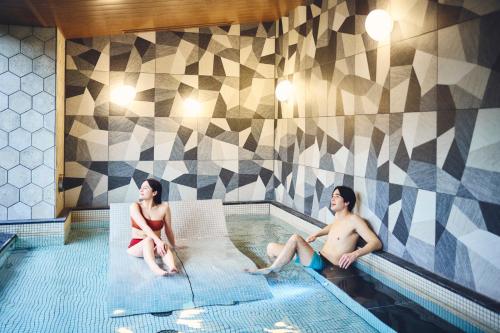 a man and woman sitting in a swimming pool at Hotel Indigo Hakone Gora by IHG in Hakone