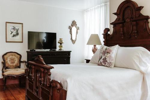 a bedroom with a large bed and a chair at Maison Mouton Bed & Breakfast in Lafayette