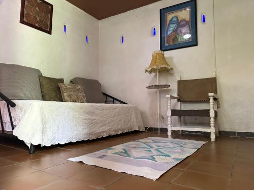 een woonkamer met een bed en een stoel bij Owl House in Piedades