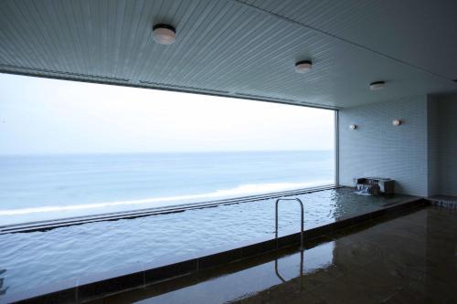 a swimming pool in a building with a large window at Shimoda Prince Hotel in Shimoda