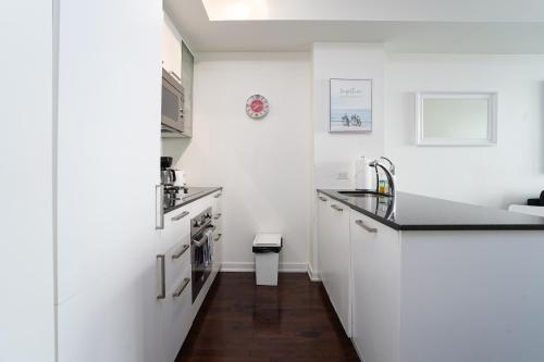 uma cozinha com armários brancos e um balcão preto em Downtown Toronto condo 2 bedrooms with parking near Rogers Center em Toronto