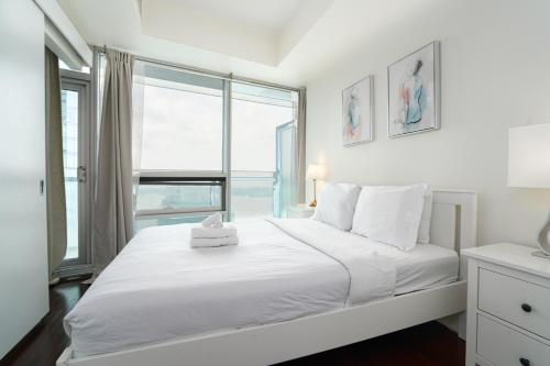 een slaapkamer met een wit bed en een groot raam bij Downtown Toronto condo 2 bedrooms with parking near Rogers Center in Toronto