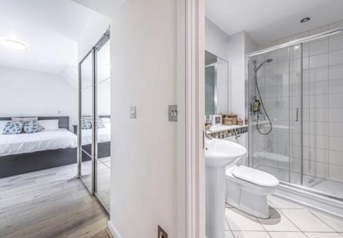 a bathroom with a shower and a toilet and a bed at Welcome To Your Home in London